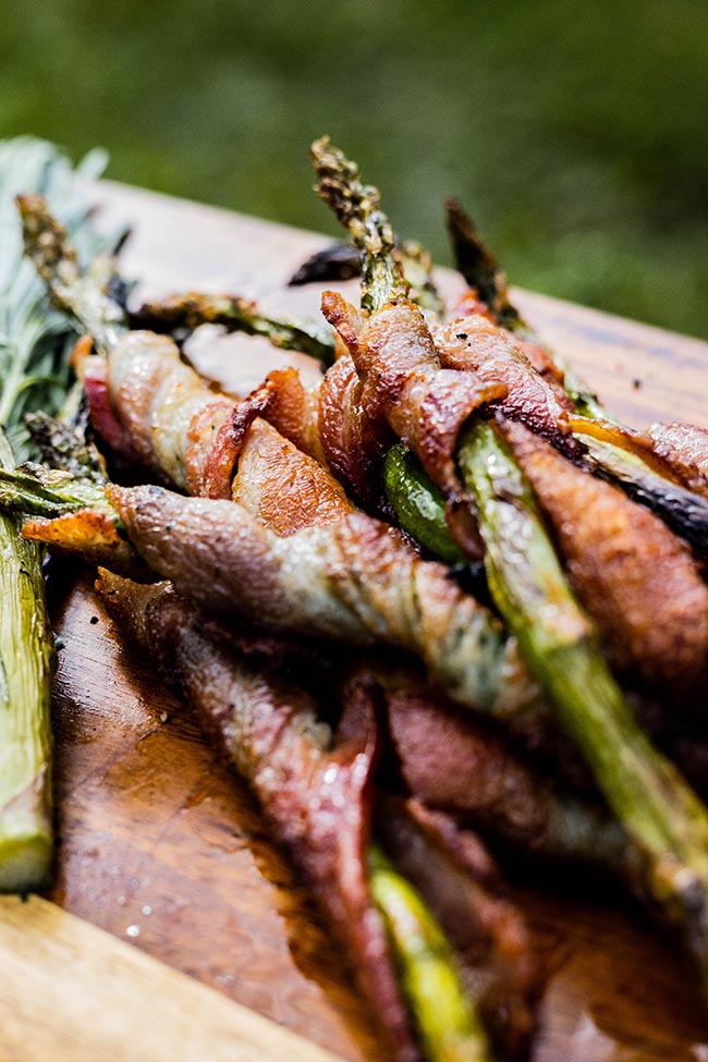 wooden platter holding delicious bacon wrapped asparagus
